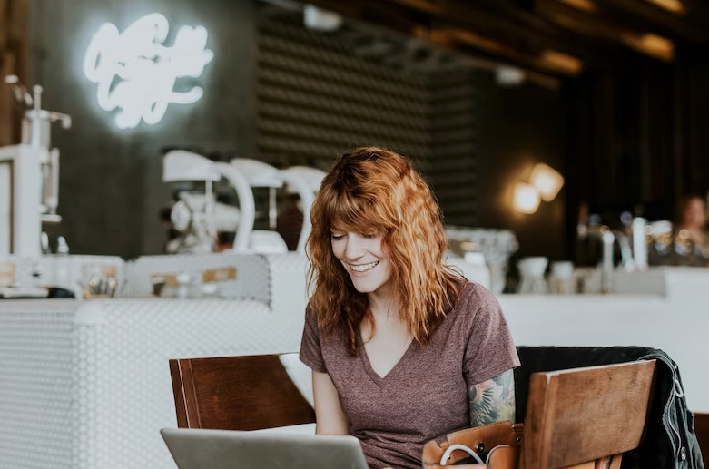 Woman smiling and looking at laptop. Photo Unsplash ID:11786ced9454